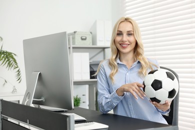 Photo of Happy woman with soccer ball at table in office