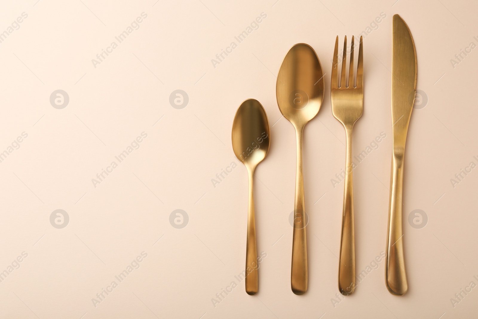 Photo of Stylish cutlery set on beige table, flat lay. Space for text