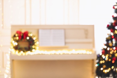 Photo of Blurred view of white piano with fairy lights indoors. Christmas music