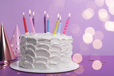 Photo of Delicious cake with burning candles and festive decor on purple background. Space for text