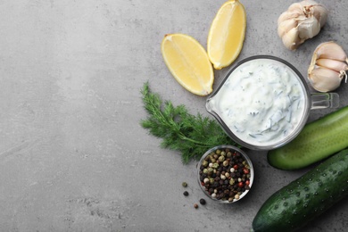 Photo of Cucumber sauce with garlic, lemon, dill and pepper on grey background, top view. Space for text