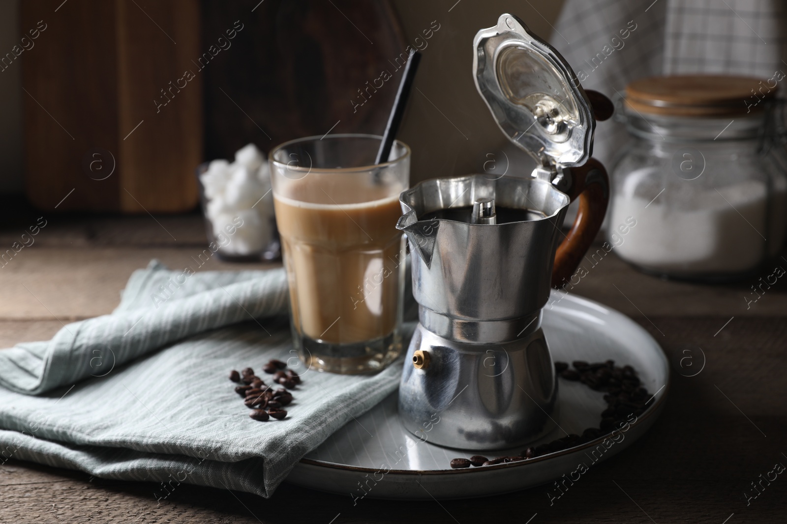 Photo of Brewed coffee in moka pot, glass of drink and beans on wooden table