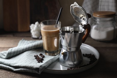 Photo of Brewed coffee in moka pot, glass of drink and beans on wooden table