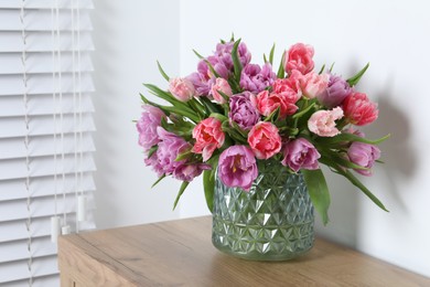 Beautiful bouquet of colorful tulip flowers on wooden table indoors