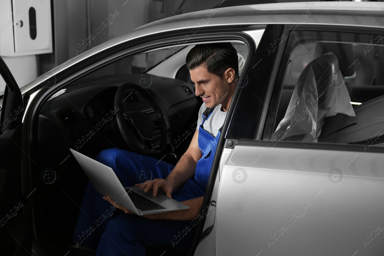 Photo of Mechanic with laptop doing car diagnostic at automobile repair shop