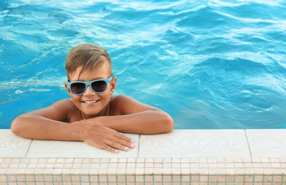 Happy cute boy with sunglasses in swimming pool