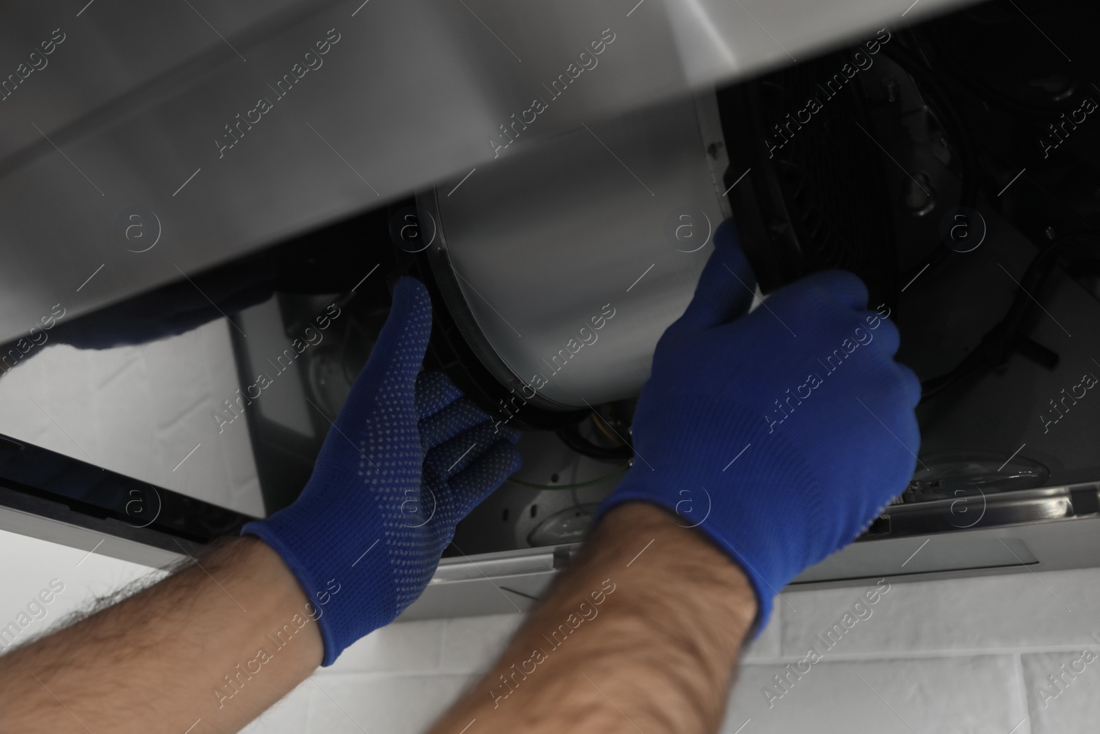 Photo of Worker repairing modern cooker hood indoors, closeup