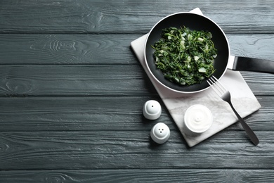 Photo of Tasty cooked spinach served on dark wooden table, flat lay with space for text. Healthy food