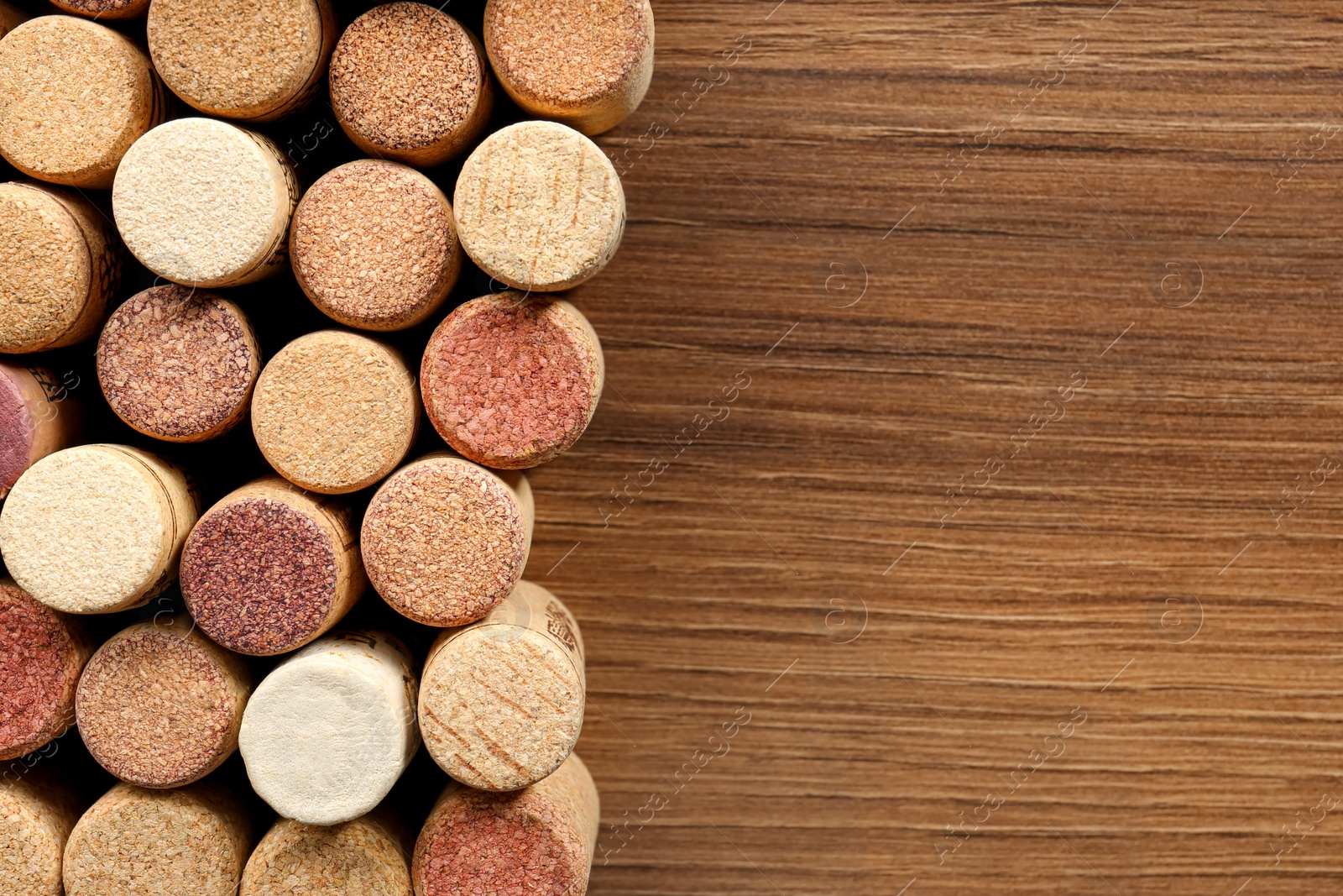 Photo of Flat lay composition with many corks of wine bottles on wooden table. Space for text