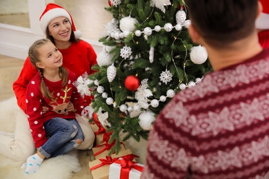 Happy family with cute child decorating Christmas tree together at home