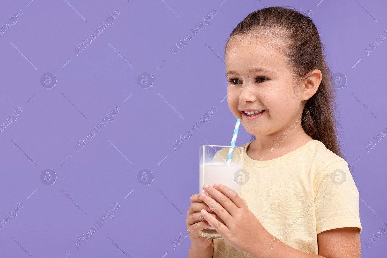 Photo of Cute girl with glass of fresh milk on violet background, space for text