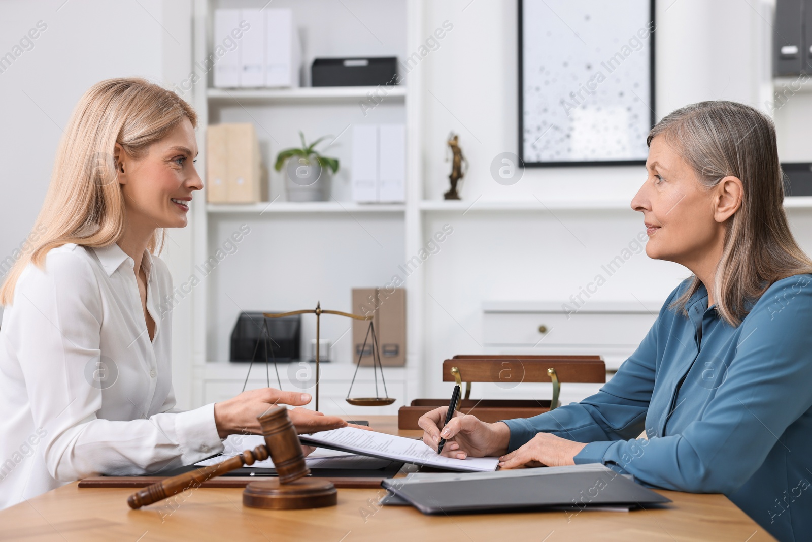 Photo of Senior woman signing document in lawyer's office