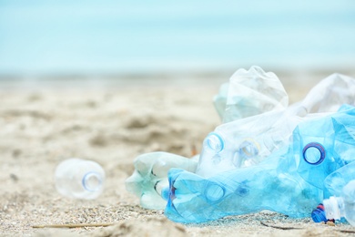 Used plastic bottles on beach, space for text. Recycling problem