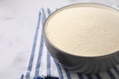 Photo of Bowl of uncooked organic semolina on white marble table, closeup. Space for text