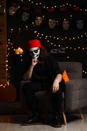 Photo of Man in scary pirate costume with skull makeup against blurred lights indoors. Halloween celebration