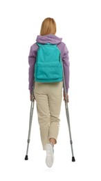 Photo of Young woman with axillary crutches on white background, back view