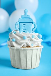 Photo of Beautifully decorated baby shower cupcake for boy with cream and topper on light blue background