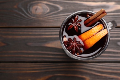 Photo of Aromatic mulled wine on wooden table, top view. Space for text