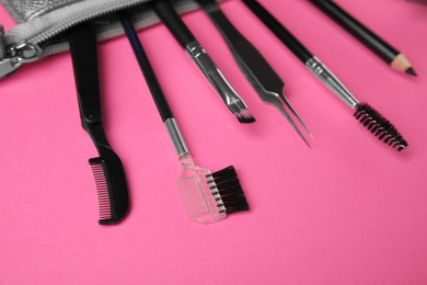 Set of professional eyebrow tools on pink background