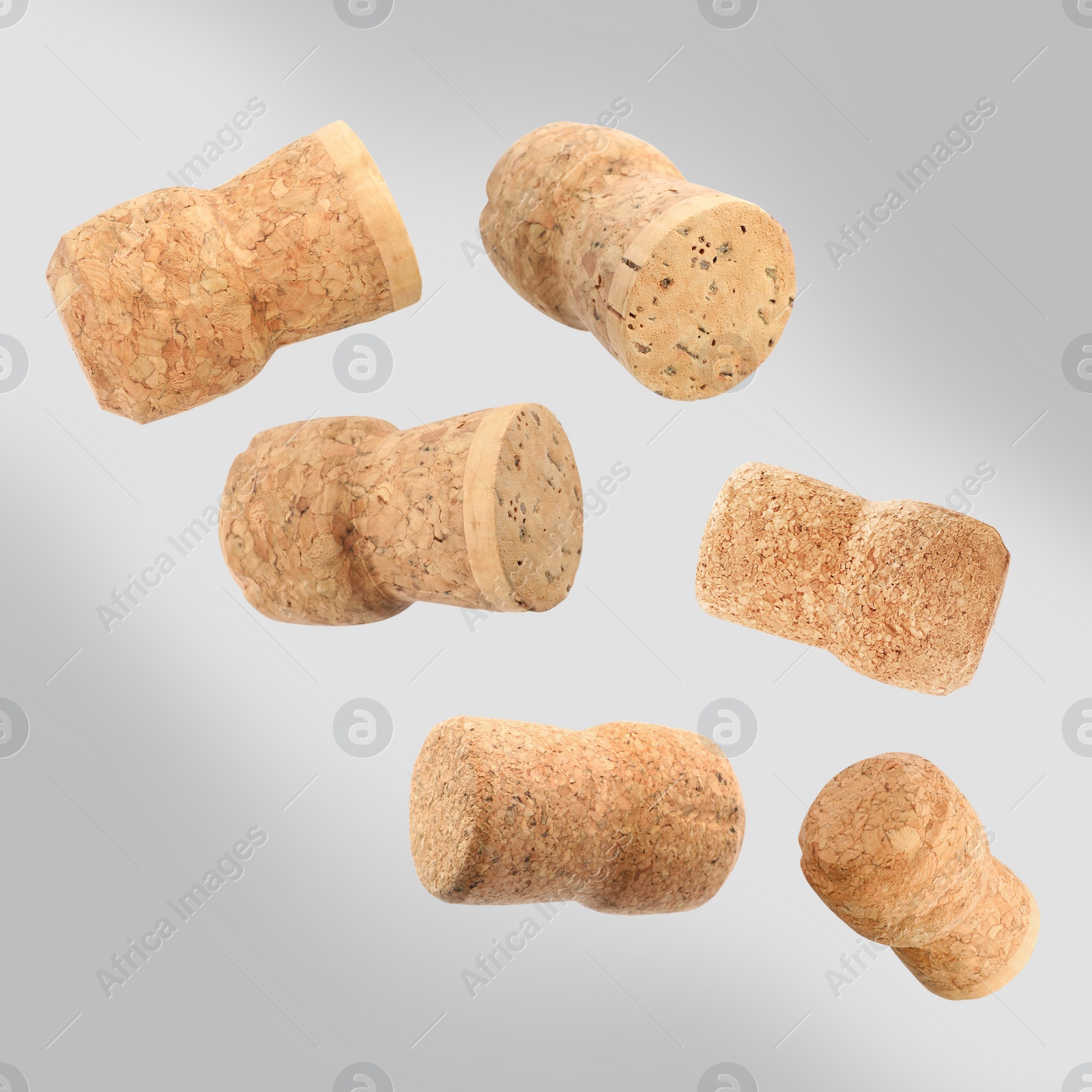 Image of Many corks of sparkling wine bottles falling on light grey background