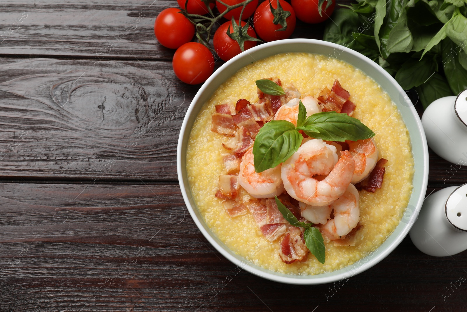 Photo of Fresh tasty shrimps, bacon, grits and basil in bowl on wooden table, flat lay. Space for text