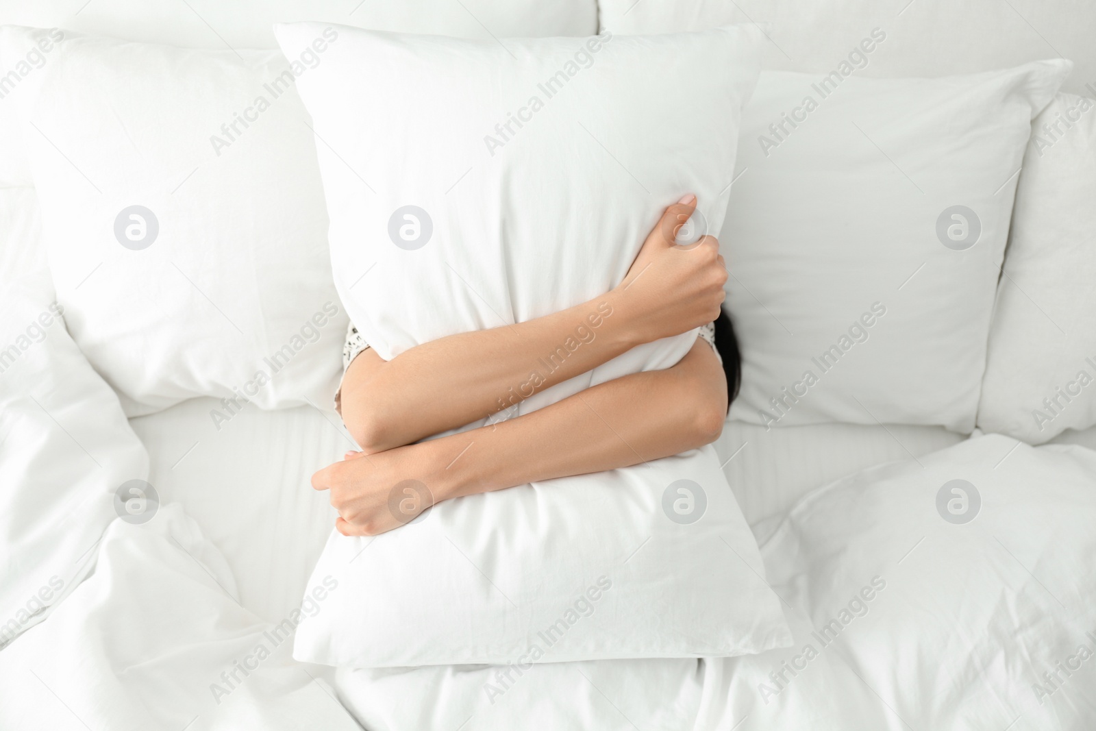 Photo of Young woman with pillow in bed, top view. Lazy morning