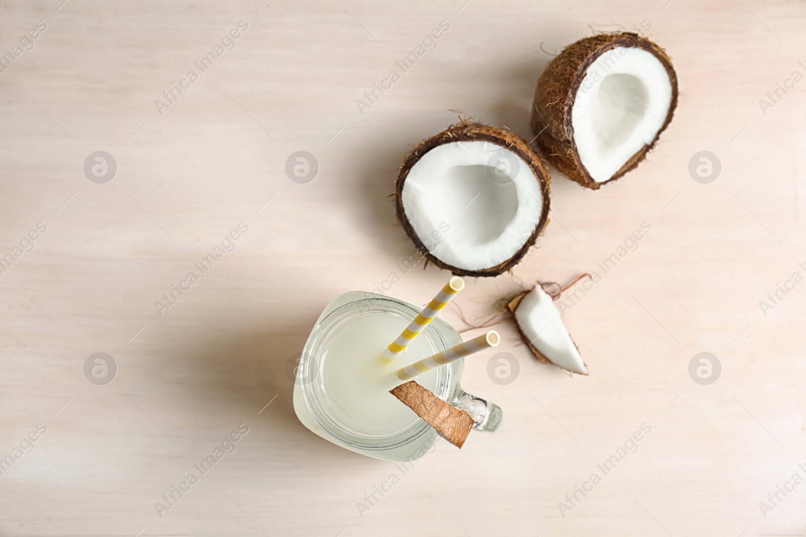 Photo of Mason jar with coconut water and fresh nuts on table, top view