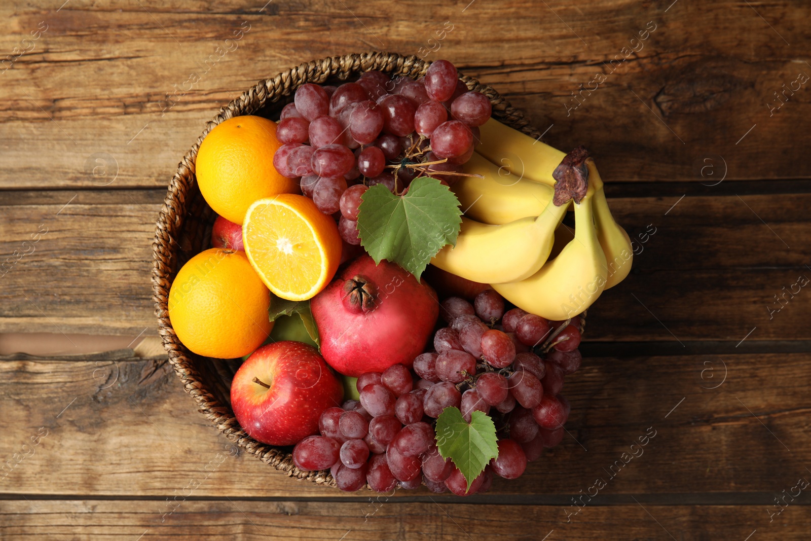 Photo of Wicker basket with different fruits on wooden table, top view