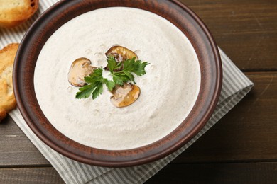 Photo of Fresh homemade mushroom soup in ceramic bowl on wooden table