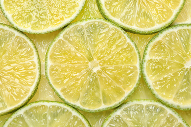 Many fresh juicy lime slices as background, top view