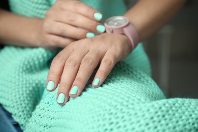 Photo of Young woman with stylish mint manicure and knitted plaid, closeup