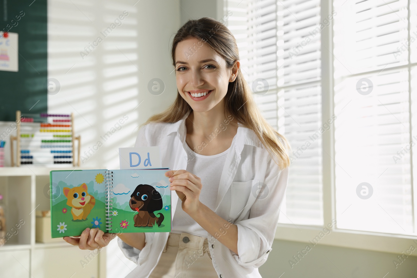 Photo of Happy female English teacher giving lesson in elementary school