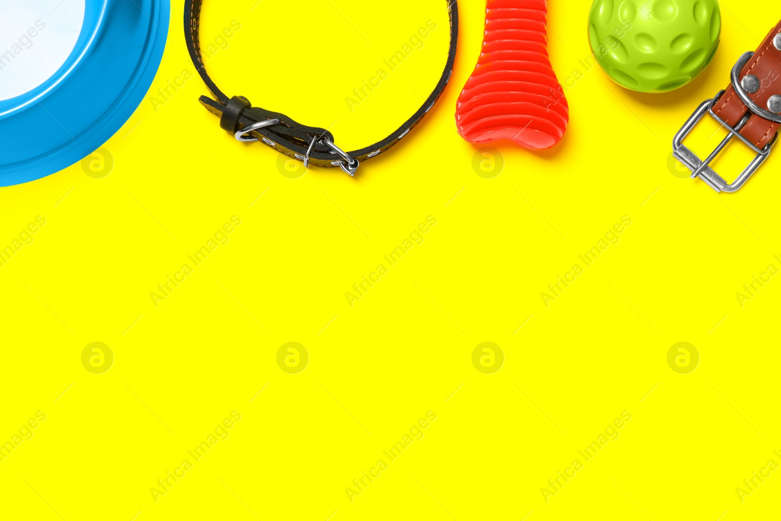 Photo of Flat lay composition with dog collar and toys on yellow background. Space for text