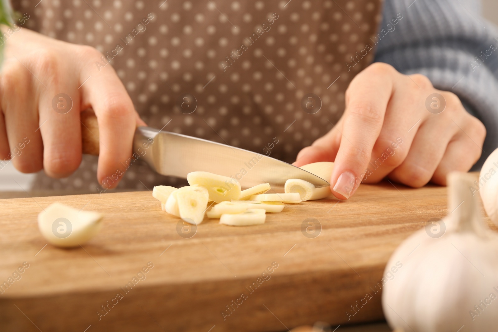 Photo of Woman cutting fresh garlic at table, closeup