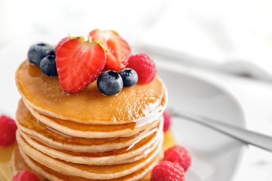 Photo of Tasty pancakes with berries and honey on plate, closeup