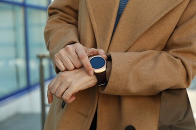 Mature woman using smart watch outdoors, closeup