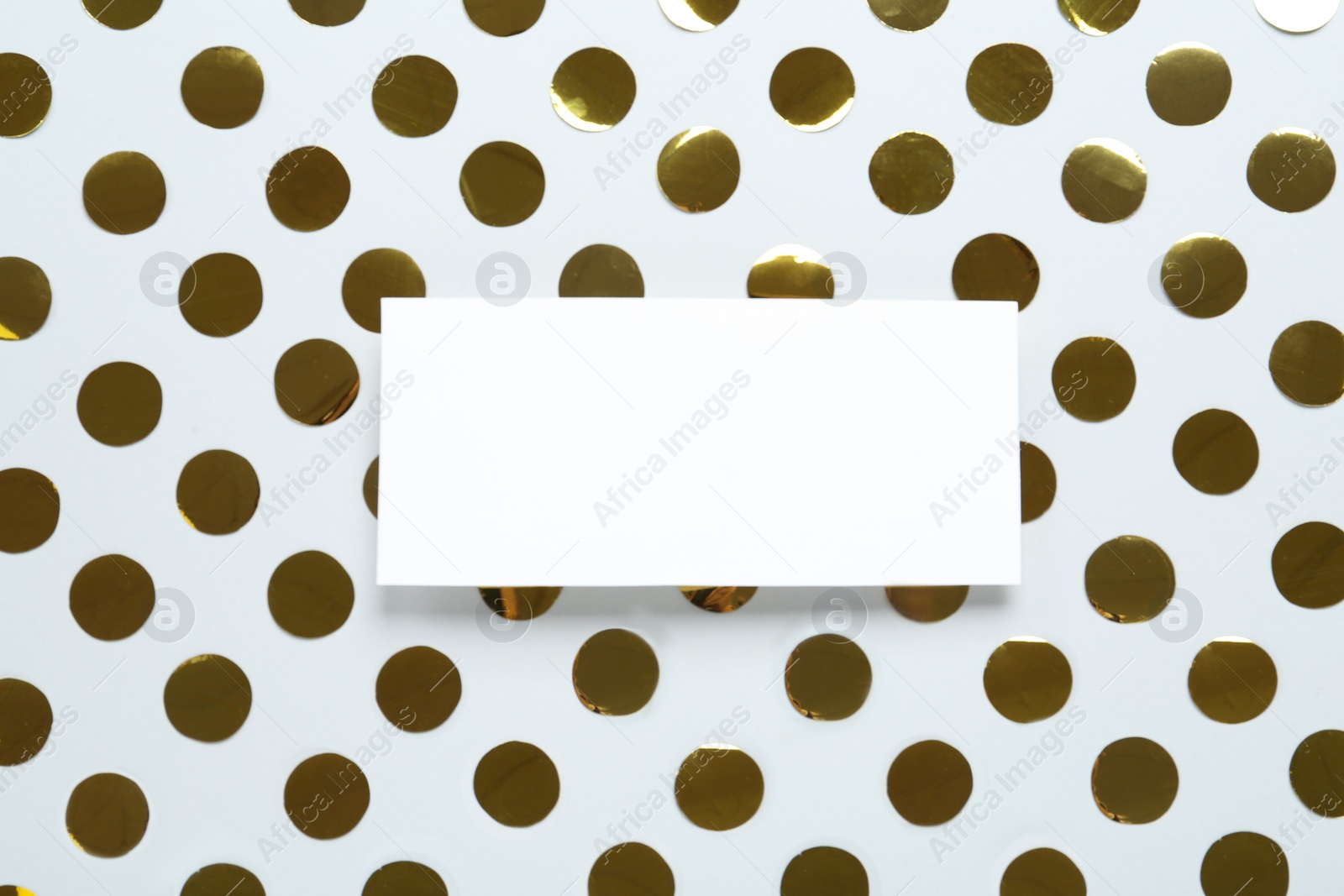 Photo of Blank card and shiny golden confetti on white background, flat lay. Space for text