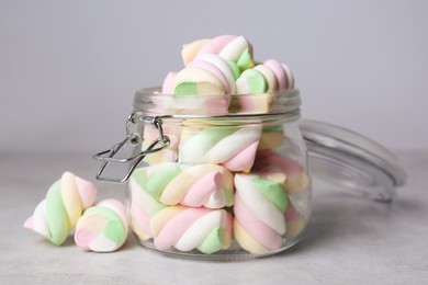 Glass jar with delicious colorful marshmallows on light grey table, closeup