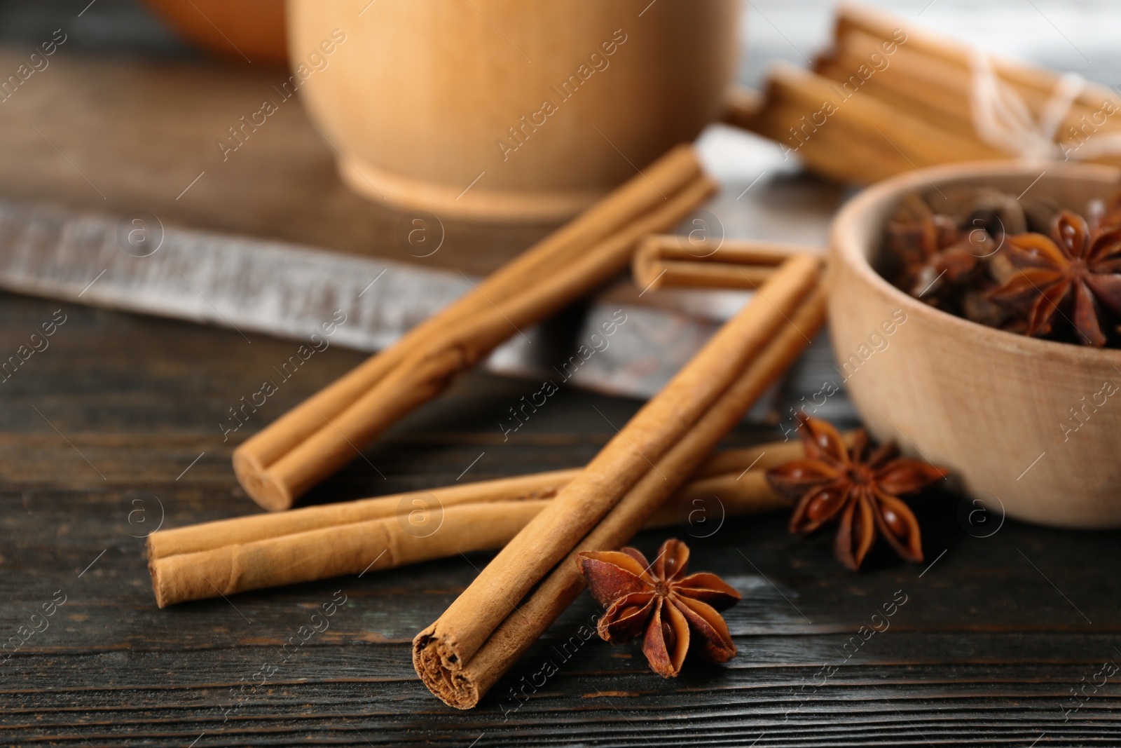 Photo of Aromatic cinnamon sticks and anise on wooden table, closeup