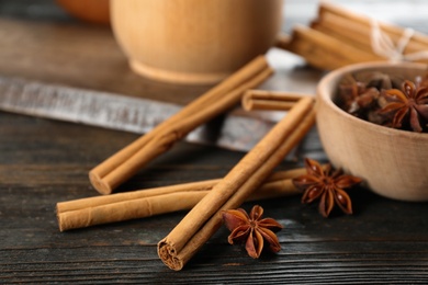 Aromatic cinnamon sticks and anise on wooden table, closeup