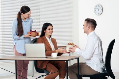 Photo of Colleagues presenting gifts to woman in office