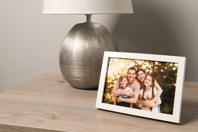 Photo of Frame with family photo and lamp on wooden table indoors