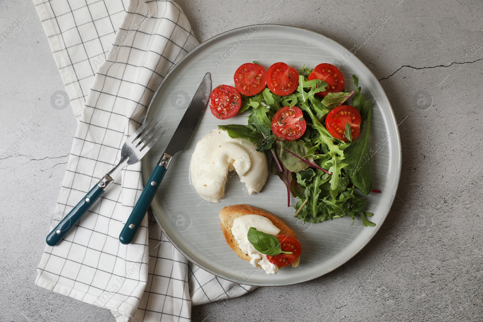 Photo of Delicious burrata cheese with tomatoes, arugula and toast served on grey table, top view