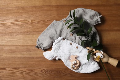 Photo of Flat lay composition with children's clothes, toys and pacifier on wooden table. Space for text