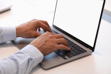 Man using modern laptop at white desk, closeup