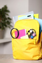 Photo of Yellow backpack with different school stationery on table indoors
