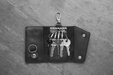 Photo of Open leather holder with keys on grey table, top view