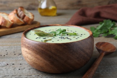 Bowl of delicious asparagus soup on wooden table