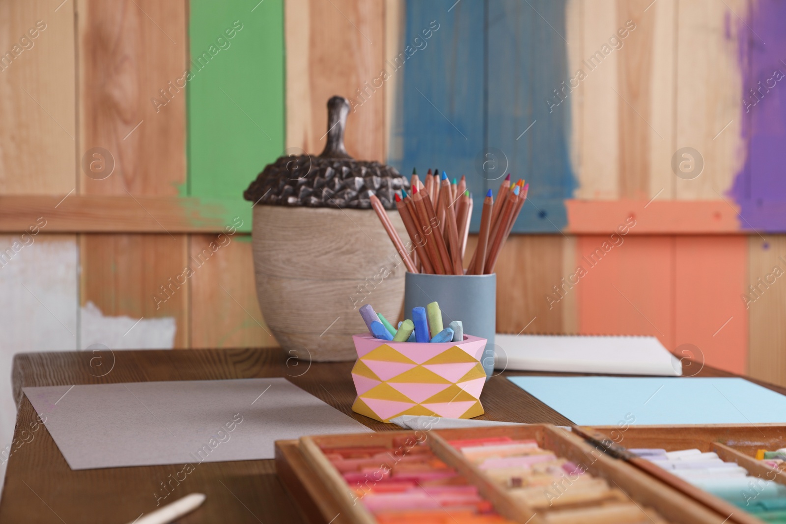 Photo of Blank sheets of paper, colorful chalk pastels and drawing pencils on wooden table indoors. Modern artist's workplace