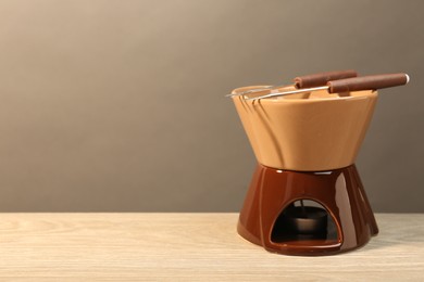 Fondue set on wooden table, space for text